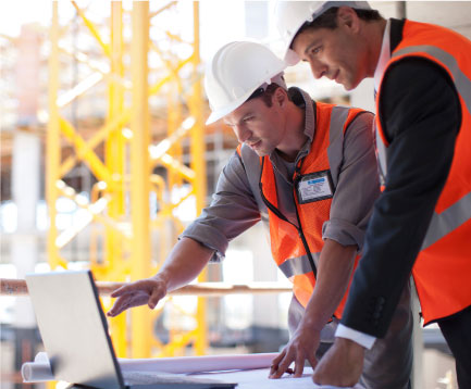 Two site managers reviewing plans on a laptop